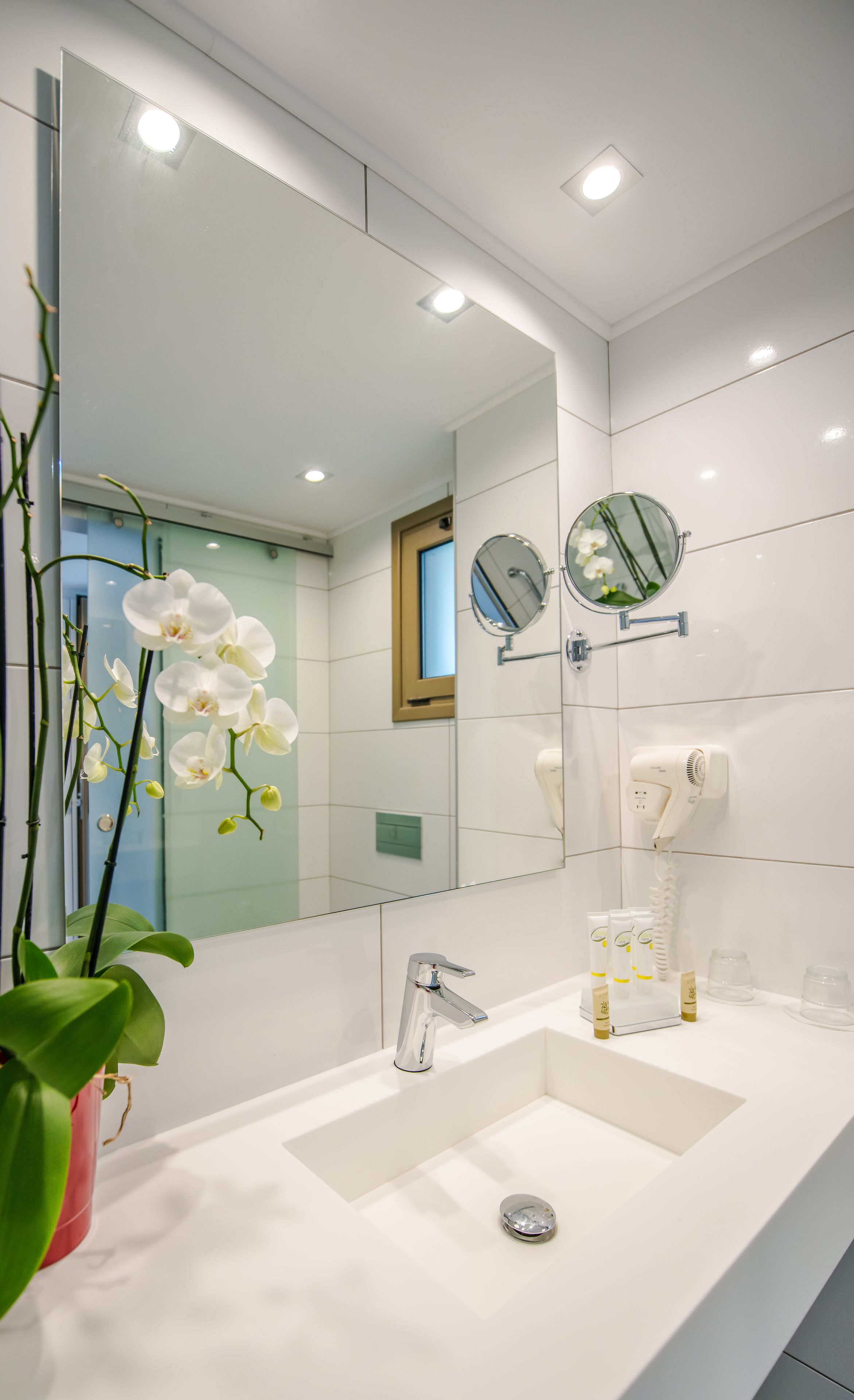 Un bagno moderno con lavandino bianco, uno specchio e un asciugacapelli.