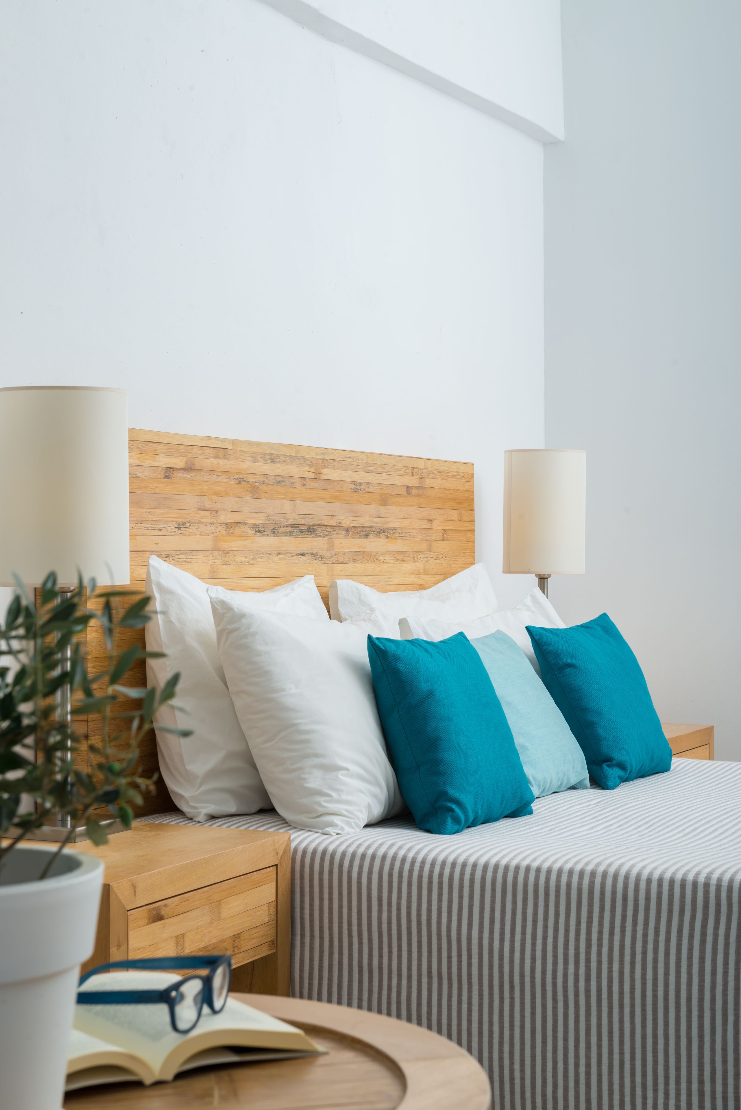 Een keurig opgemaakt hotelkamer met een houten hoofdeinde, een gestreept sprei en een nachtkastje met een lamp en een boek.
