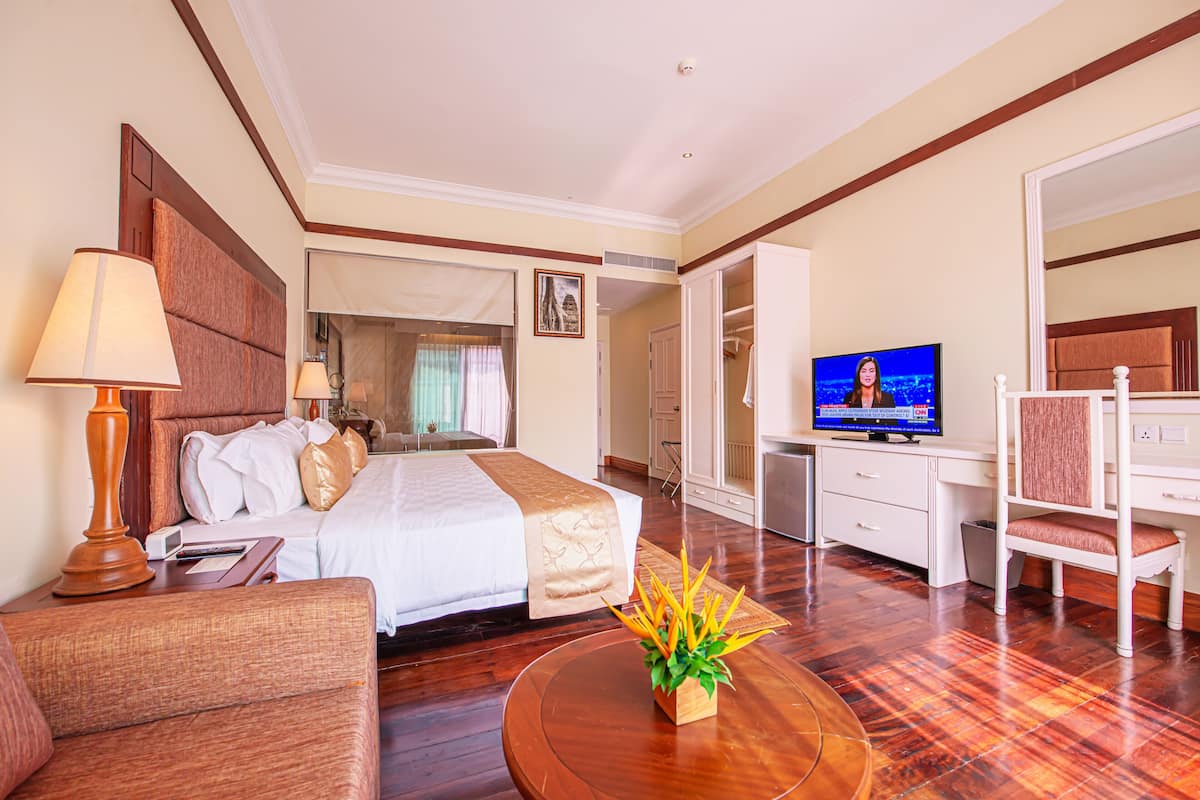 Ein Hotelzimmer mit Bett, Nachttisch, Lampe, Fernseher und Schreibtisch mit Stuhl.