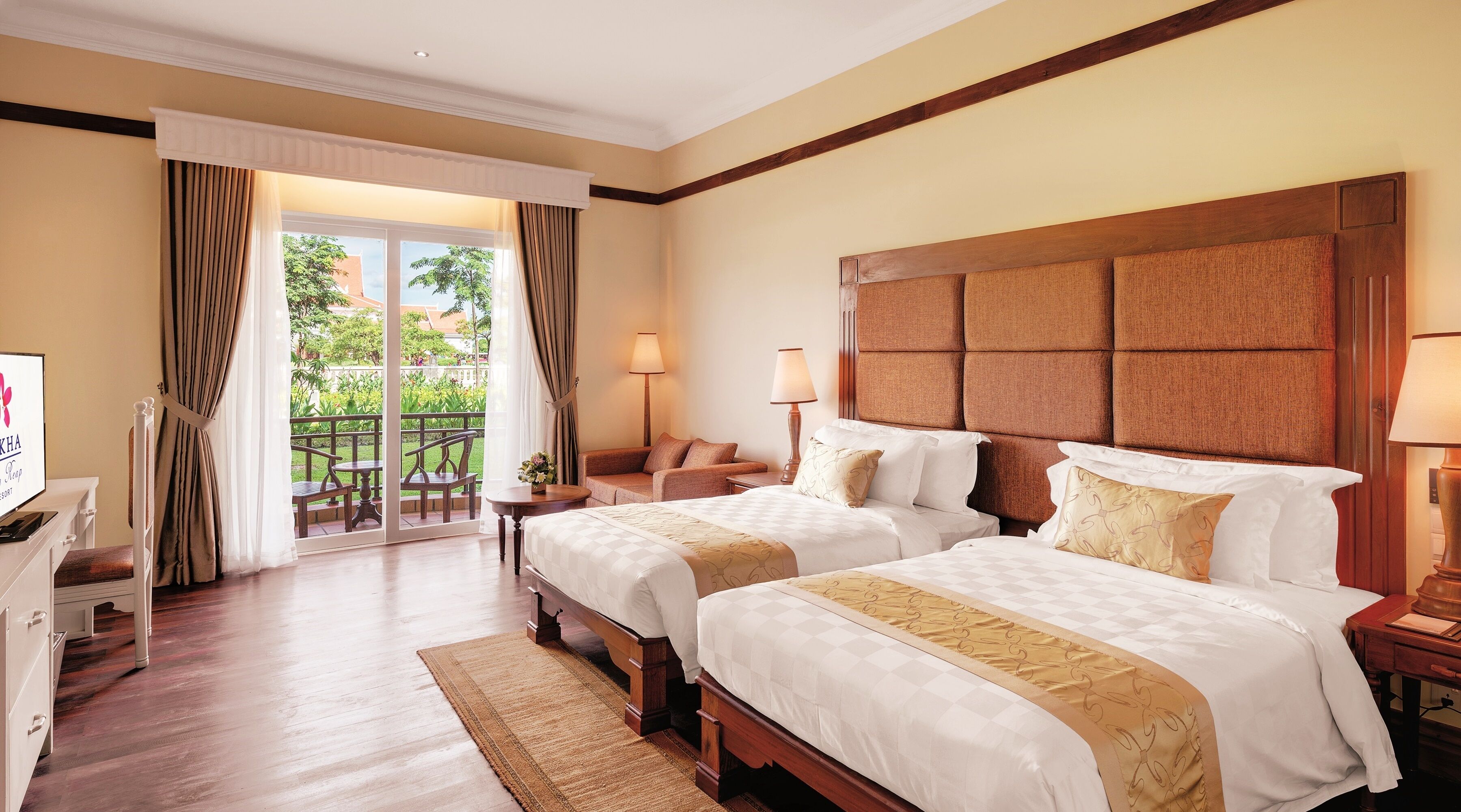A hotel room with two beds, a desk, a chair, a balcony with a view, and a television.