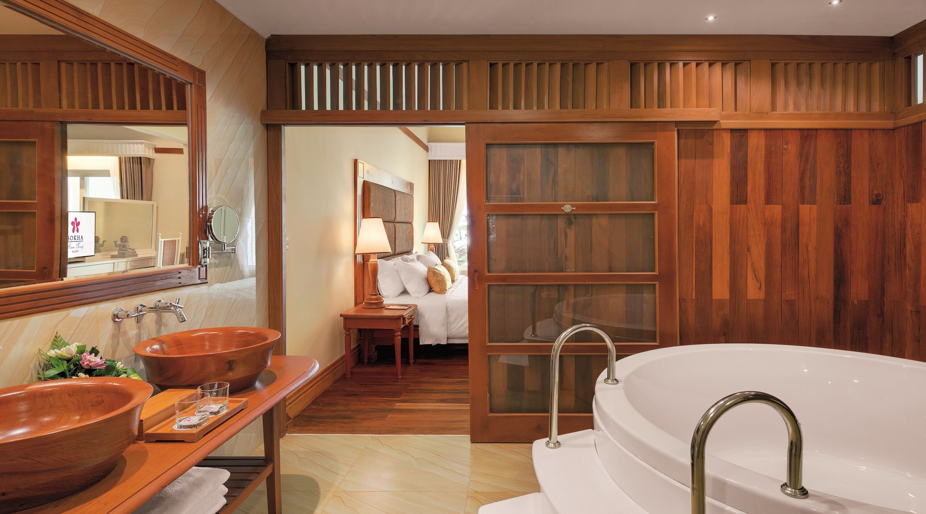 A spacious bathroom with a large bathtub, two wooden sinks, and a mirror.