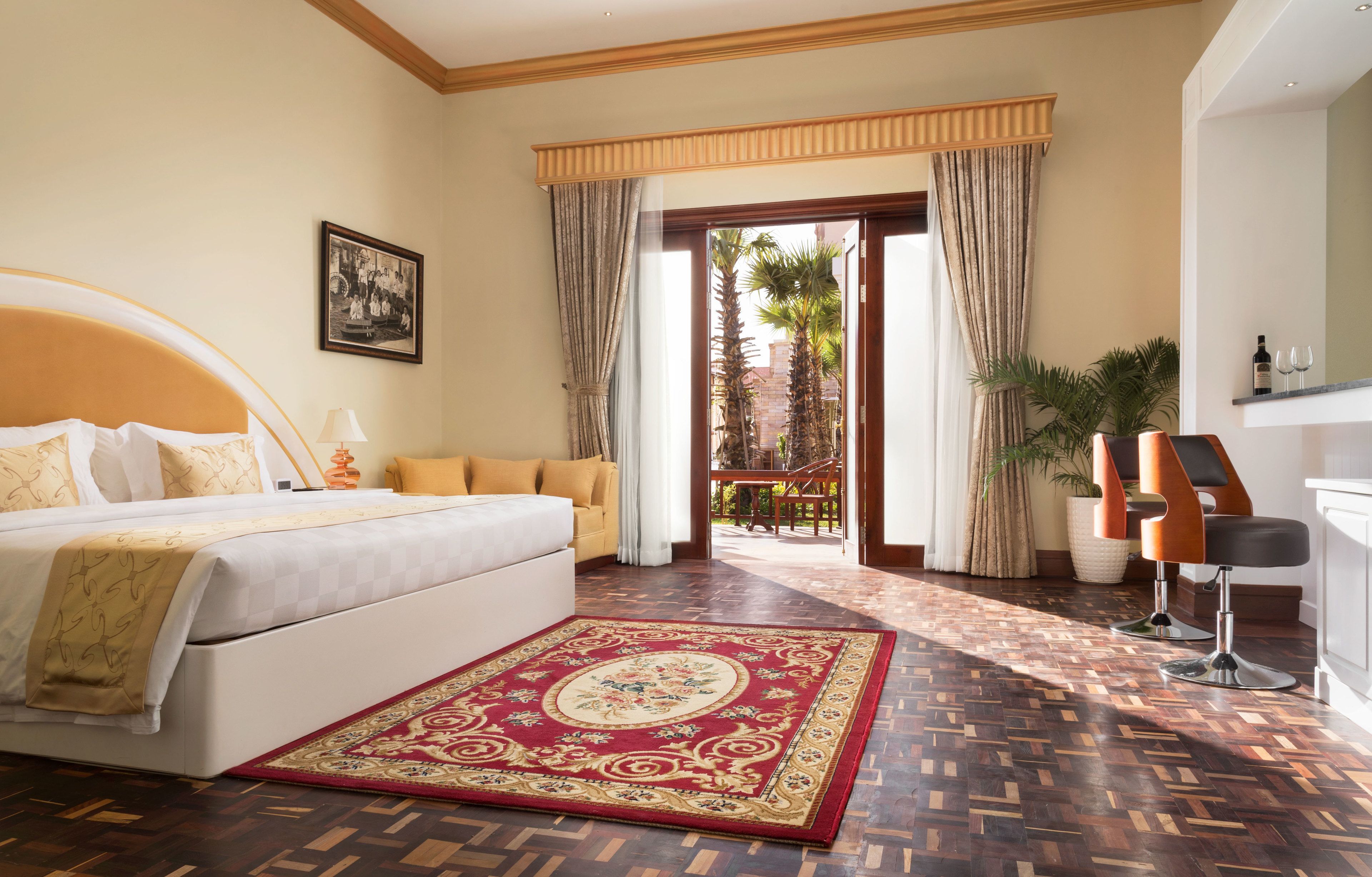 A hotel room with a bed, a sofa, a desk, and a view of the outside.