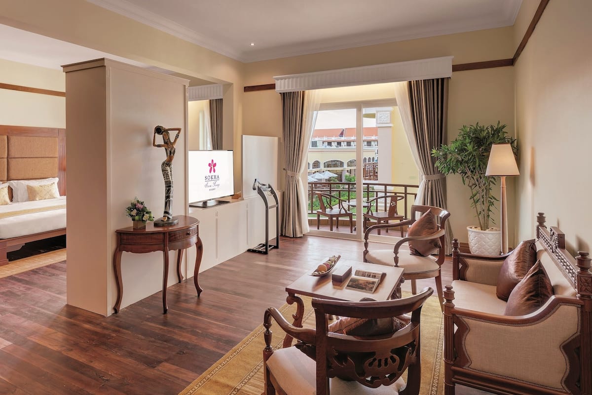 Ein Hotelzimmer mit Bett, Schreibtisch, Stuhl, Tisch und einem Balkon mit Blick.