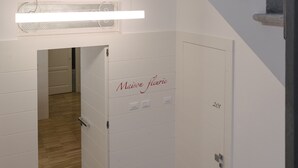 Een trap met metalen leuningen die leidt naar een kamer met een houten vloer en een deur met de tekst 'Maison florie'.