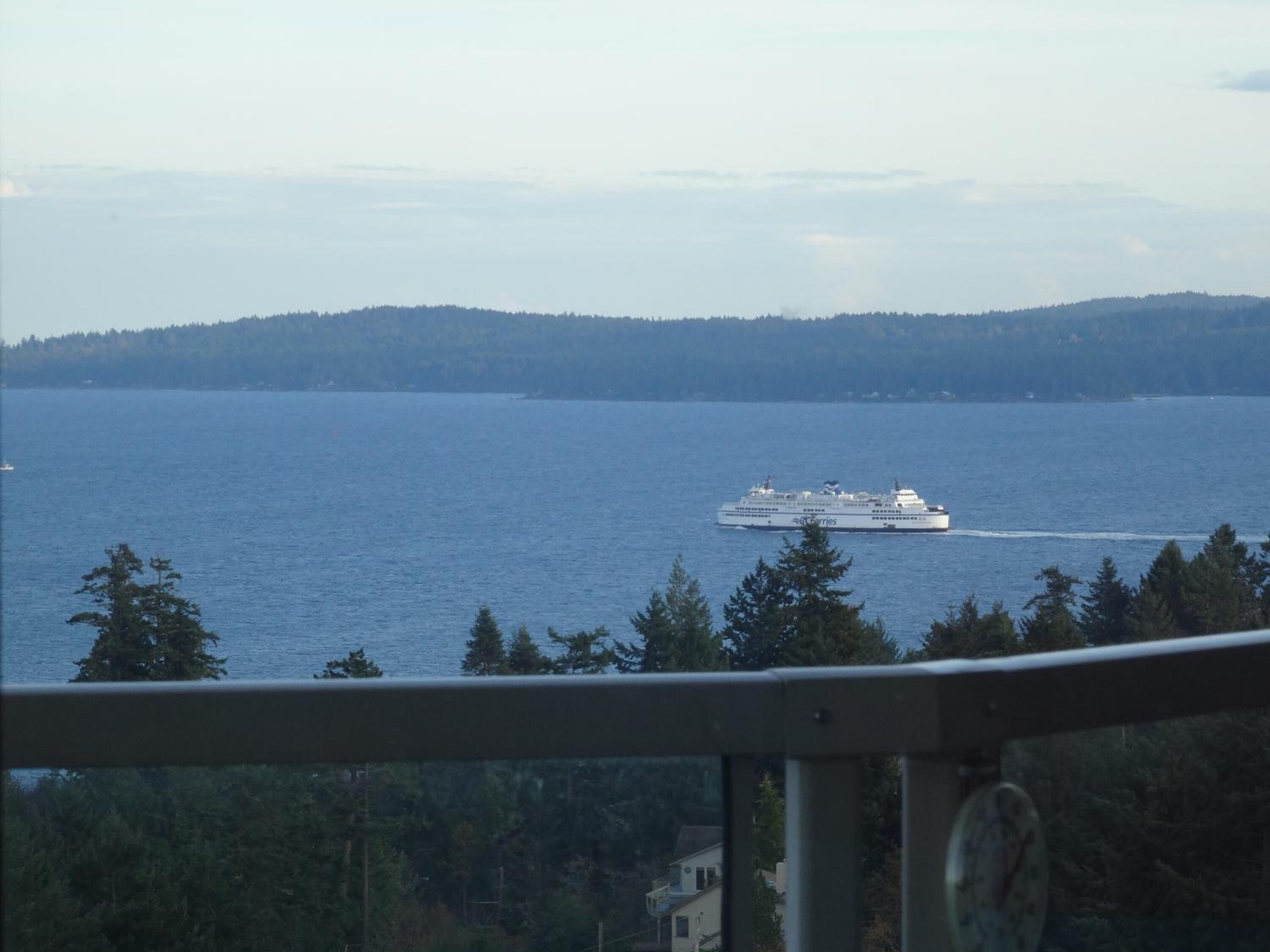 A ferry on a large body of water with a forested shoreline in the background.
