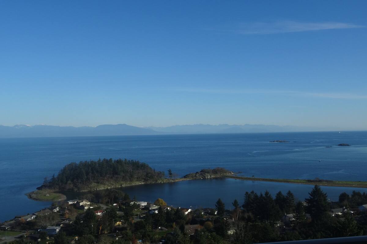 Un pueblo costero con un lago, casas y montañas a lo lejos.