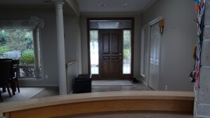 A hallway with a wooden bench, a door with glass panels, and a view of the outdoors. - Gibralter Rock Ocean View B&B (Nanaimo)