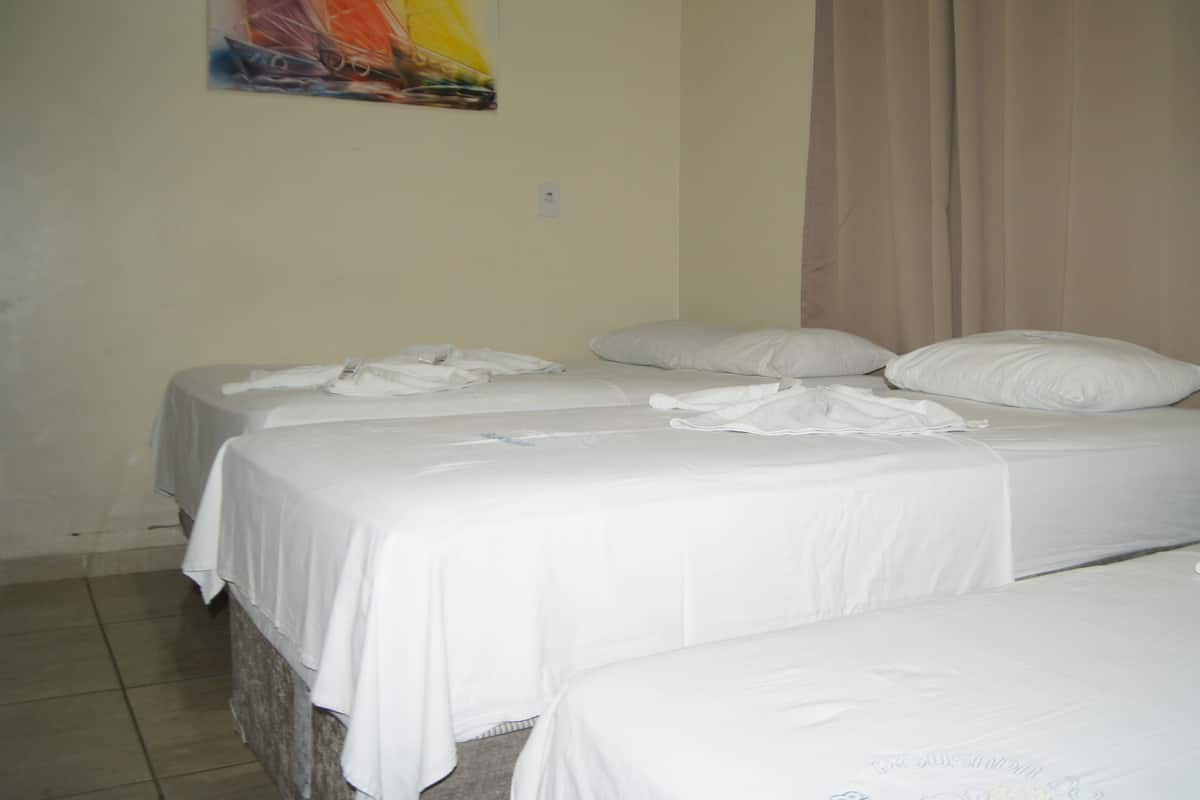 Une chambre d’hôtel avec deux lits, du linge de lit blanc, un rideau beige et un tableau coloré au mur.