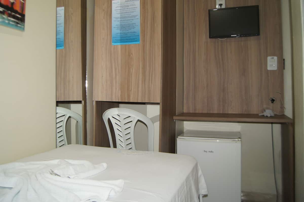 Une chambre d’hôtel avec un lit, un petit bureau avec une télévision et un réfrigérateur.