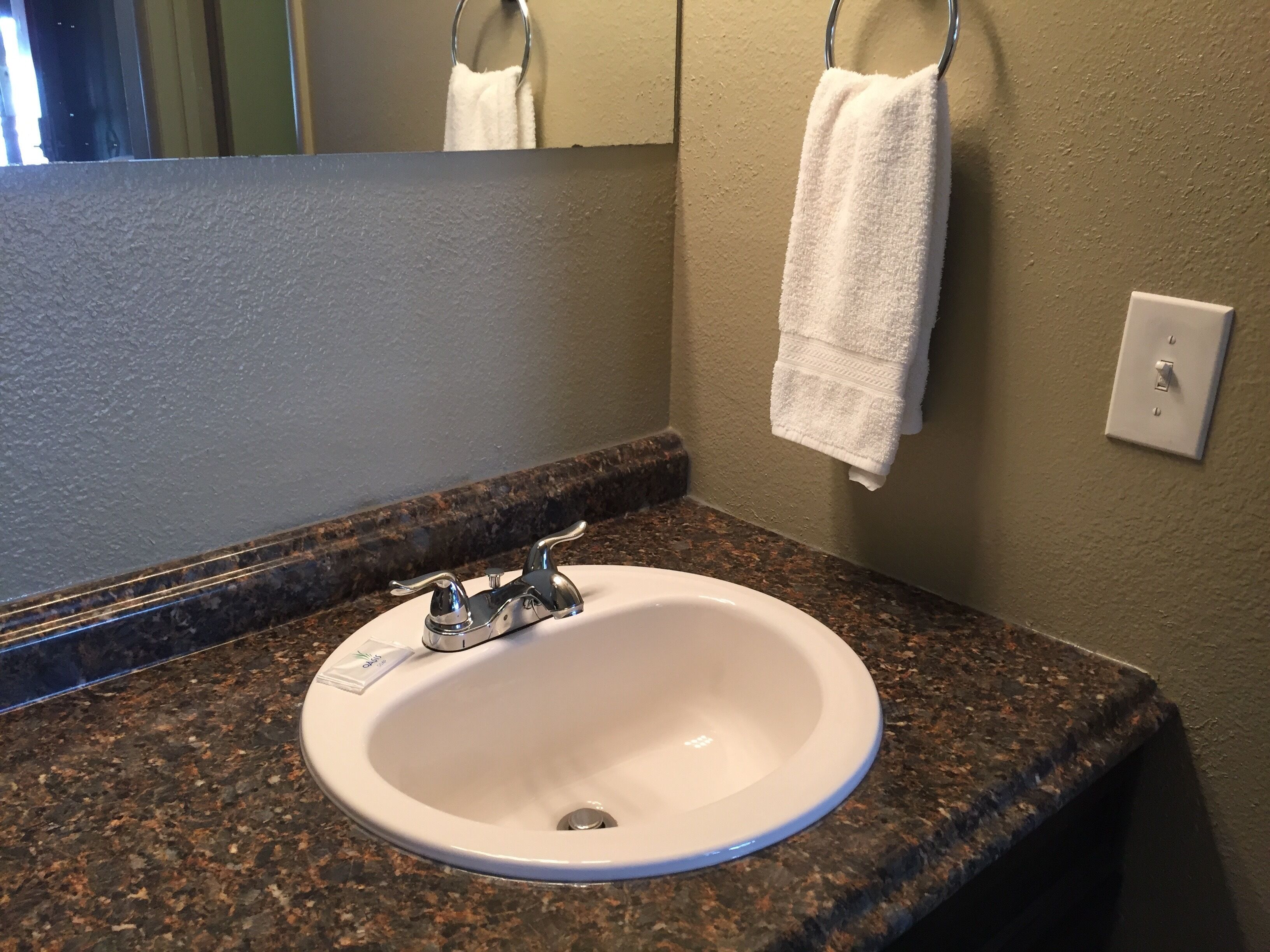 A bathroom with a white sink, granite countertop, and a mirror above it.
