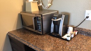 A kitchen with a microwave, coffee maker, and a coffee pod holder on the counter. - Gateway Inn (Lyman)