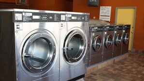 A row of industrial-style front-loading washers in a commercial setting. - Gateway Inn (Lyman)