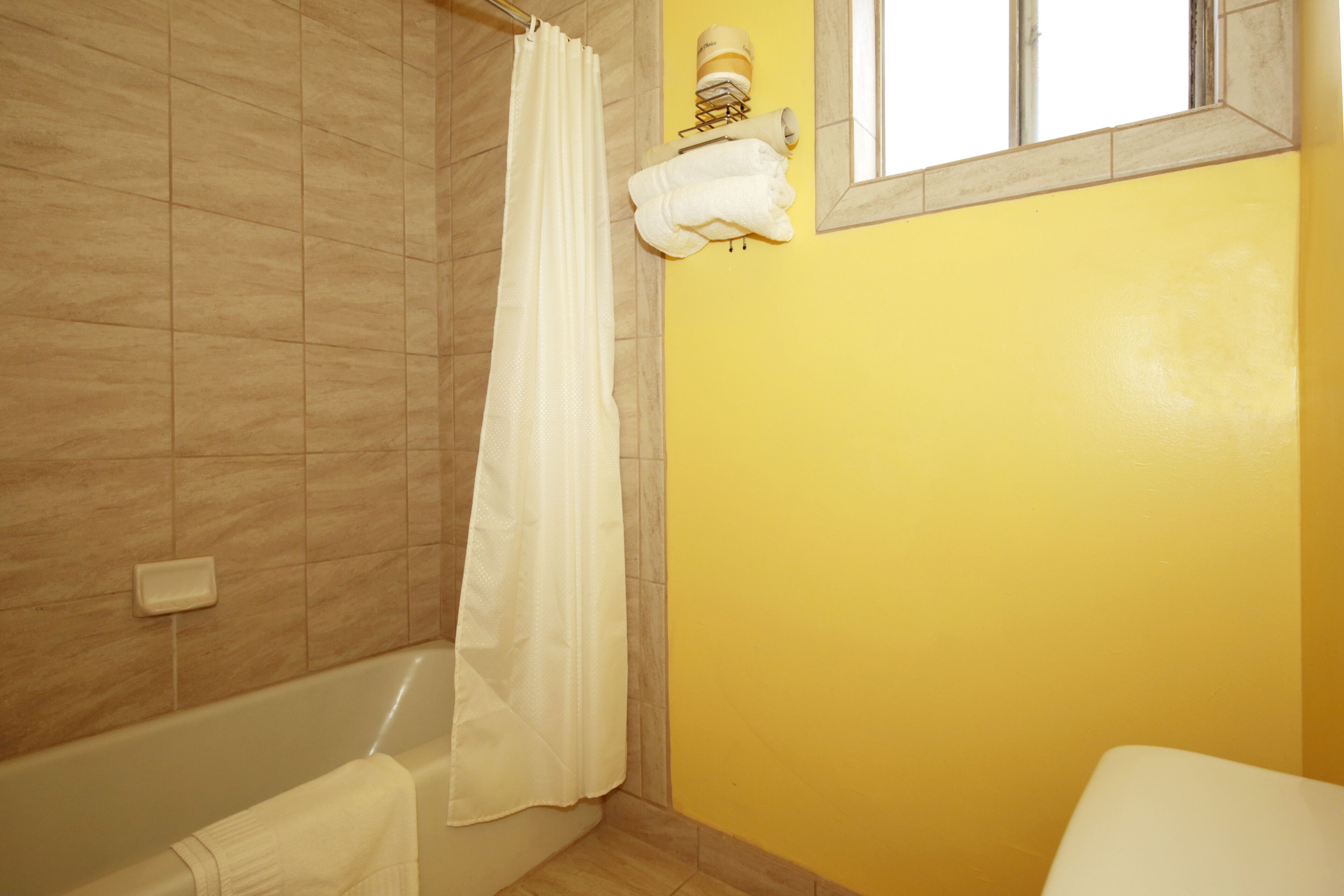 Un baño con bañera, cortina de ducha y toallero con toallas.