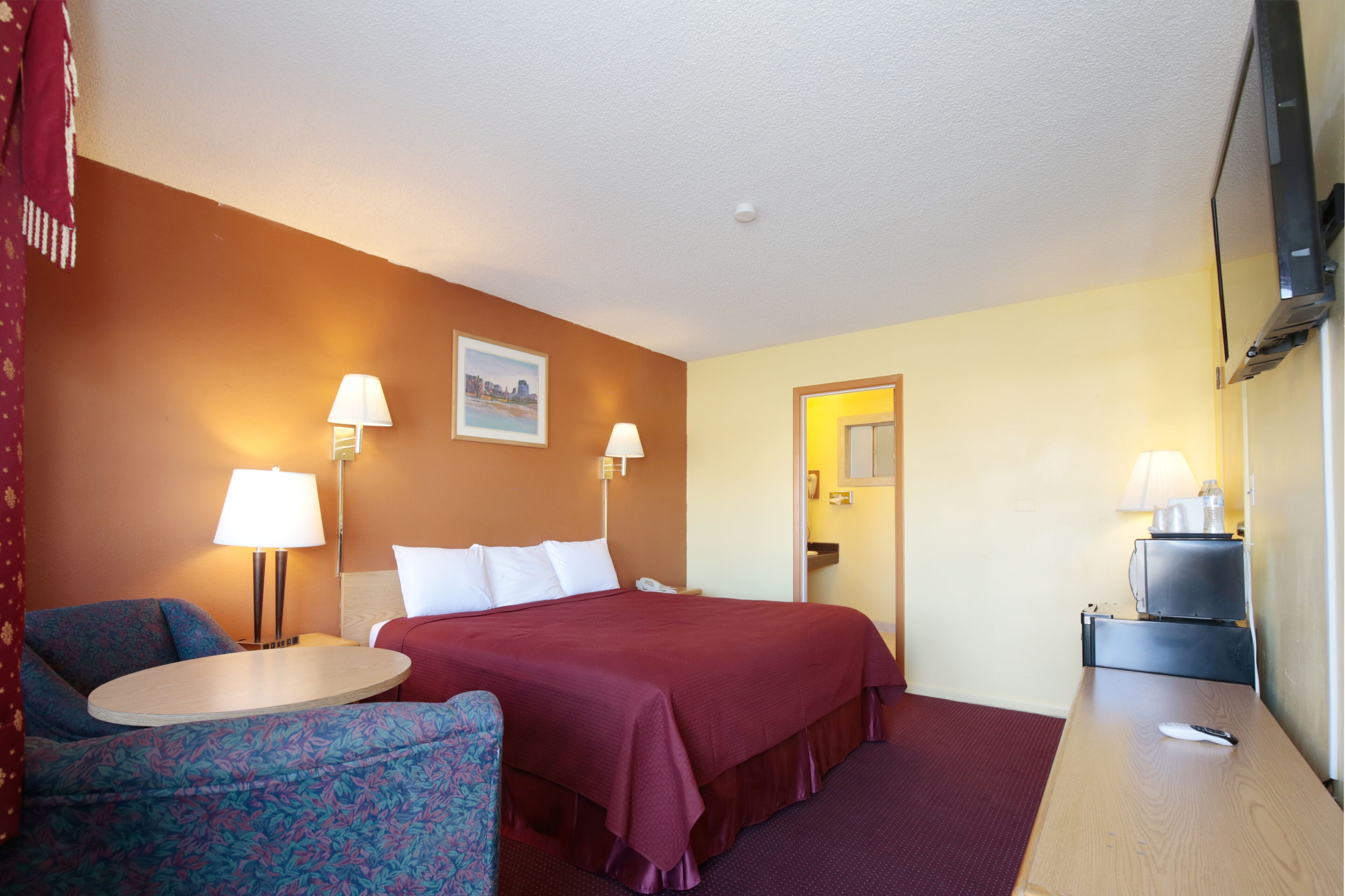 Une chambre d’hôtel comprenant un lit, deux lampes de chevet, un bureau, une chaise et un téléviseur.