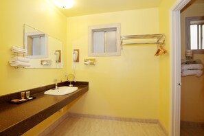 A bathroom with a sink, mirror, towel rack, and a door leading to another room.