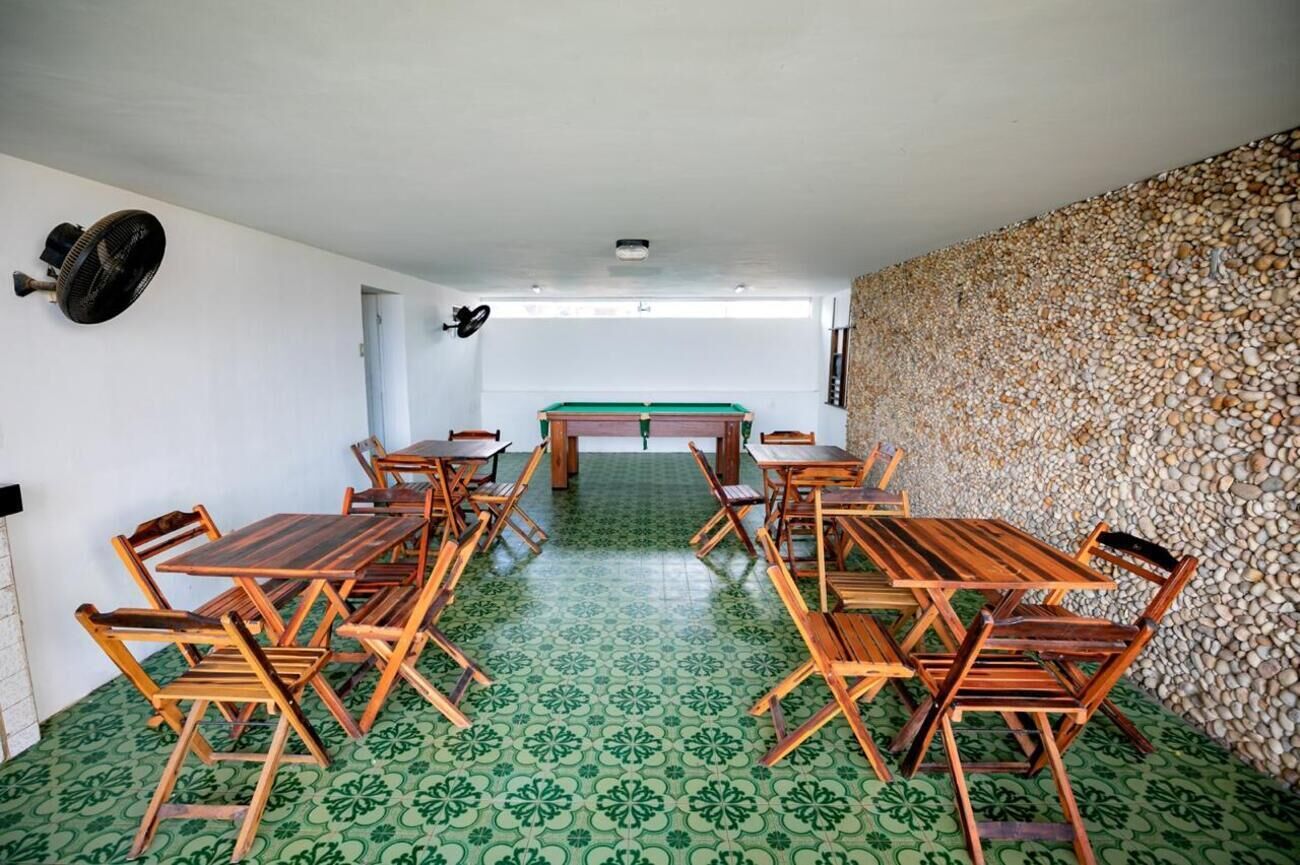 Una habitación con mesa de billar, mesas y sillas de madera, y un suelo con estampado verde.