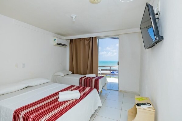 A hotel room with two beds, a TV, and a balcony with a view of the sea. - Hotel Paraíso Natal (Natal)