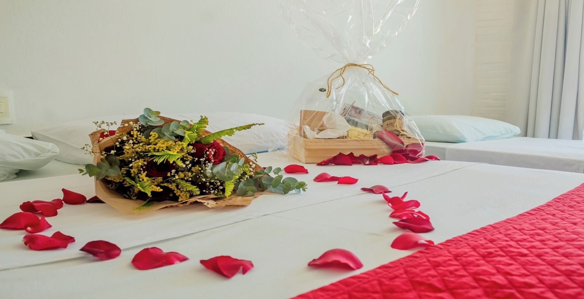 Una habitación de hotel con una cama, un ramo de flores y una pequeña caja de madera.