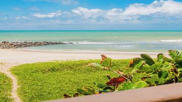 A beach with a clear view of the ocean and a rocky outcrop in the distance.