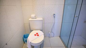 Baño con inodoro, ducha y un cubo de basura azul.