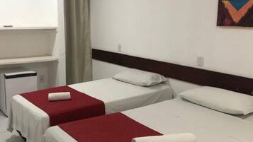 Habitación de hotel con dos camas individuales, una kitchenette pequeña y un equipo de aire acondicionado en la pared.