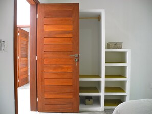 A room with a wooden door, white shelving, and a bed. - La Réserve Design Villas (Tibau do Sul)