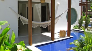 A poolside area with a hammock, wooden pergola, and a view of the pool. - La Réserve Design Villas (Tibau do Sul)