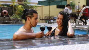 A couple in a hot tub with a pool in the background.