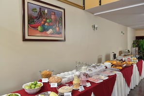 A buffet table with various food items and a painting on the wall.