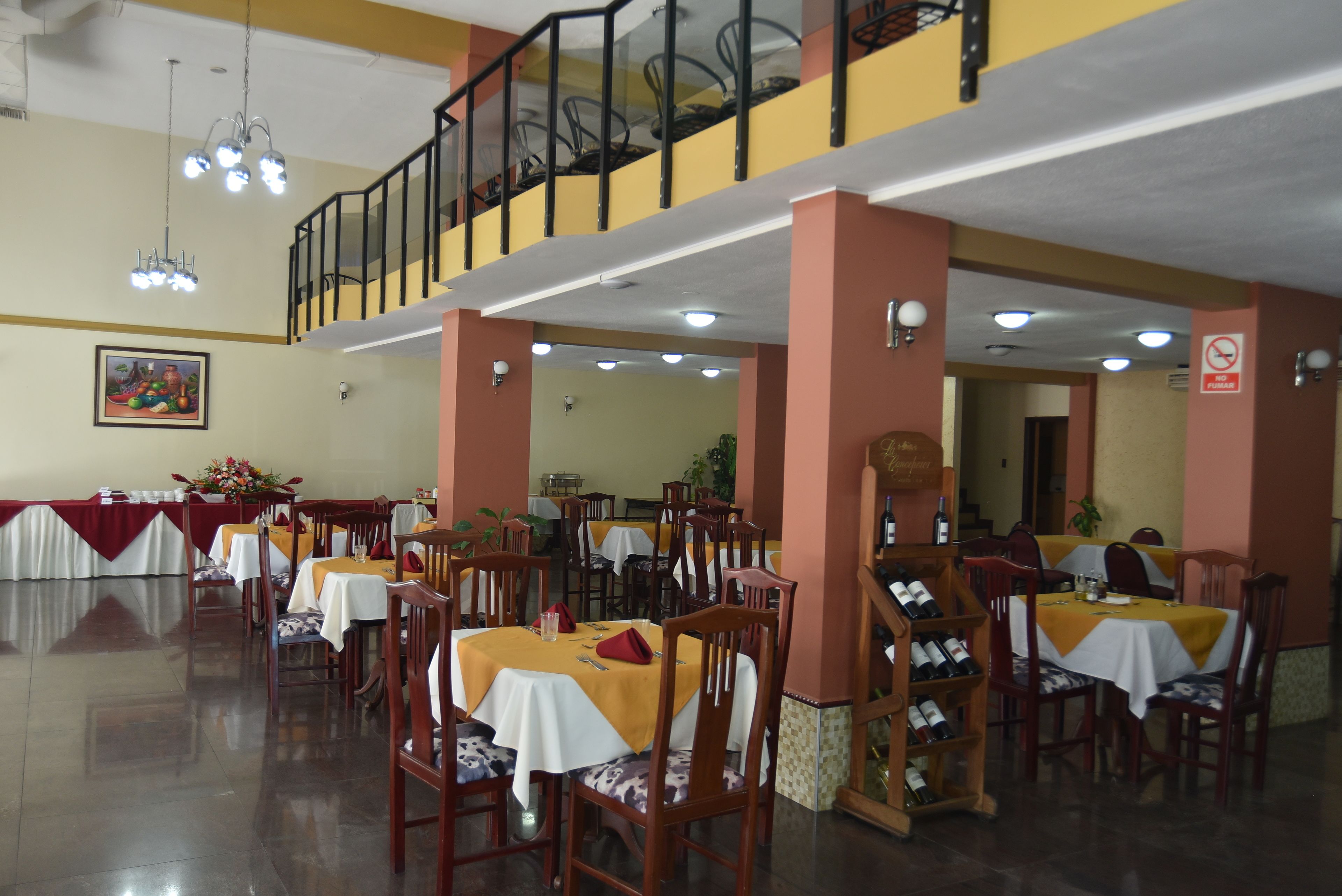 Un comedor con varias mesas y sillas, una escalera y una araña.