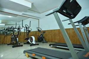 Un gimnasio con diversos equipos de ejercicio, incluyendo cintas de correr, bicicletas estáticas y elípticas.