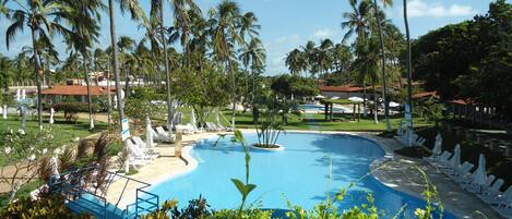 A pool surrounded by palm trees and lounge chairs.