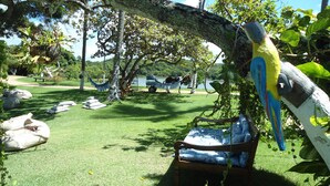 A hammock under a tree, a wooden chair, and a bird sculpture. - Fiore Resort e Residence (Paripueira)