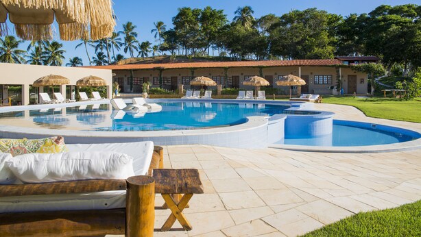 A pool area with lounge chairs, a hot tub, and a thatched-roof structure. - Fiore Resort e Residence (Paripueira)