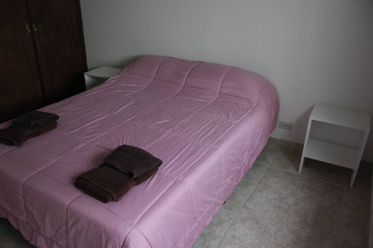 A bedroom with a large bed, a nightstand, and a wardrobe.