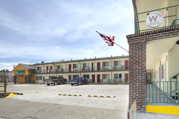 A Western Inn Motel with a two-story building, a flagpole with an American flag, and a blue pickup truck parked in front.