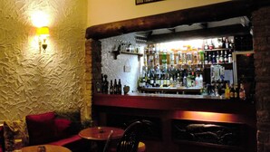 A bar area with a stone wall, wooden bar counter, and various bottles of alcohol. There are cushioned seating areas and a sign above the bar that reads "GOOD FRIENDS, GOOD WINE, GOOD TIMES." - Lowbyer Manor Country House (Alston)