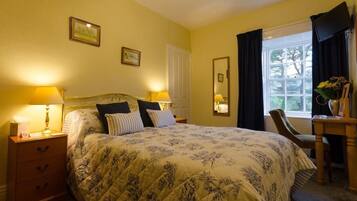 A bedroom with a bed, bedside lamps, a dresser, a chair, a window with curtains, and a mirror.