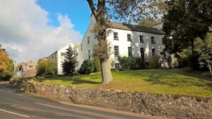 A white building with multiple windows, surrounded by a stone wall and trees. - Lowbyer Manor Country House (Alston)