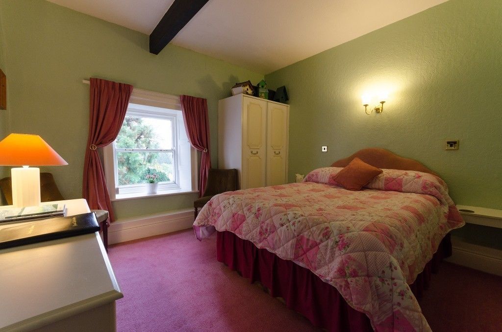 Une chambre à coucher avec un lit, un bureau avec une lampe, une fenêtre avec des rideaux et une armoire.