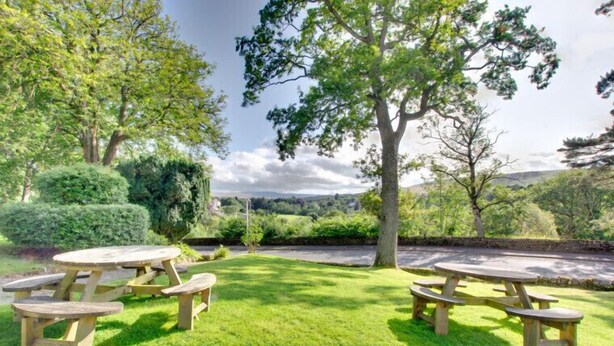 A picnic area with wooden tables and benches, surrounded by well-maintained grass and trees. - Lowbyer Manor Country House (Alston)