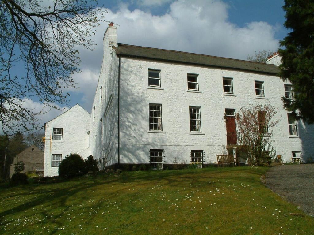 A large white building with multiple windows and a grassy lawn in front.