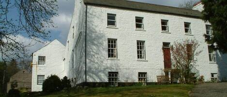 Un grand bâtiment blanc, doté de nombreuses fenêtres et précédé d’une pelouse verdoyante.