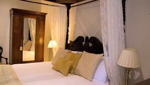 A four-poster bed with white and yellow linens, a wooden headboard, and a mirror cabinet. - Lowbyer Manor Country House (Alston)