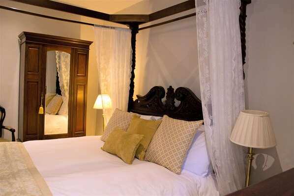 A four-poster bed with white and yellow linens, a wooden headboard, and a mirror cabinet. - Lowbyer Manor Country House (Alston)