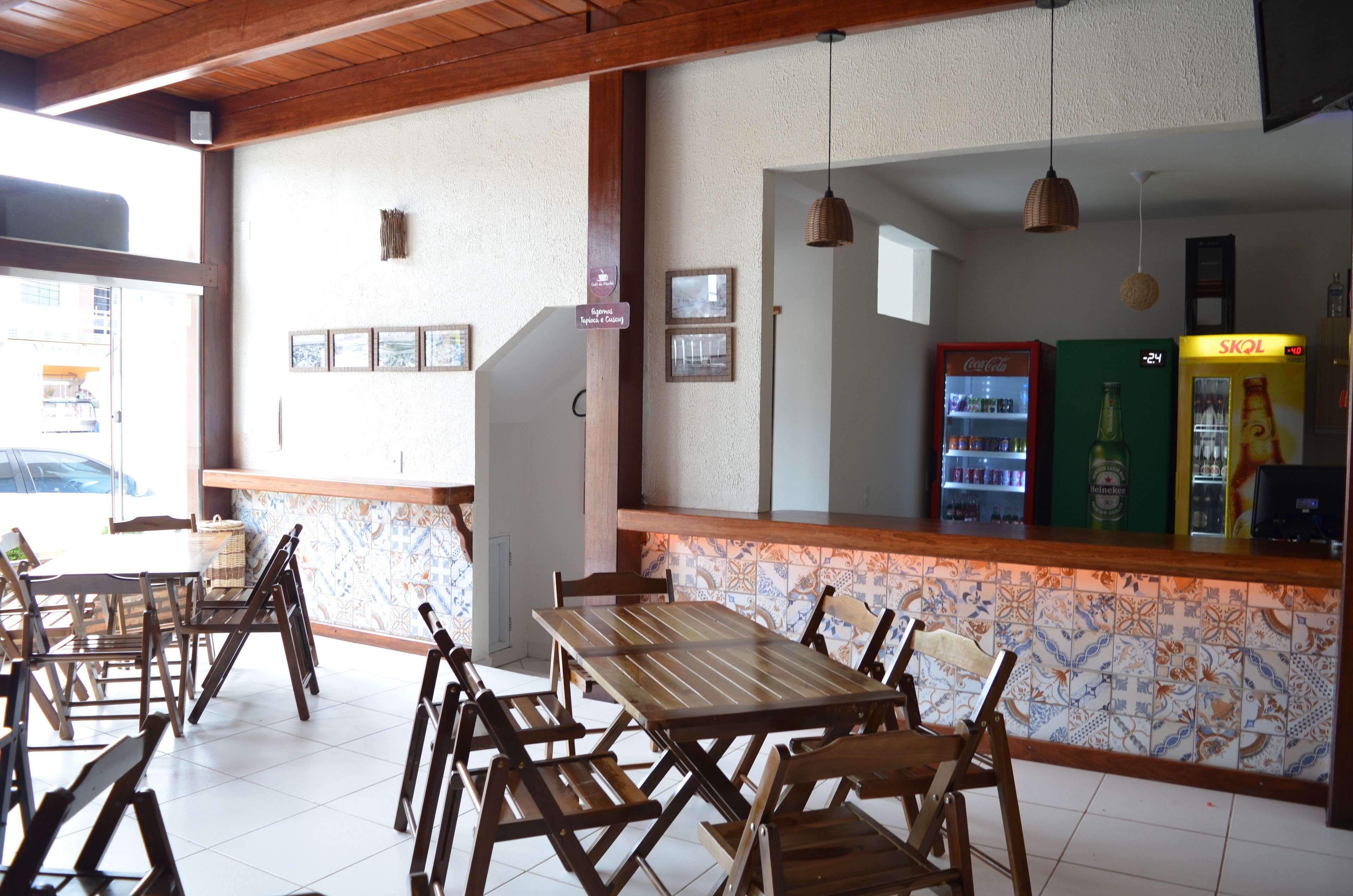 A restaurant with wooden tables and chairs, a tiled backsplash, and a Coca-Cola refrigerator.