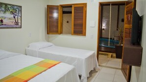 A hotel room with two single beds, a wooden door, a small pool, and a television.