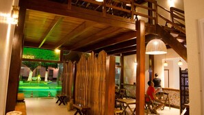 A restaurant with wooden beams, a staircase, and hanging lights.