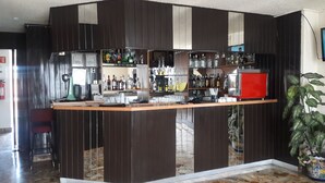 A bar area with a wooden counter, shelves with bottles, glasses, and a red cabinet. - Hotel Montreal (Mexico City)