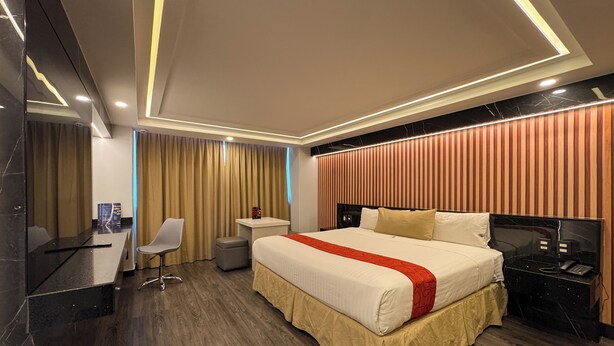 A modern hotel room with a large bed, a desk, a chair, a small table, and a nightstand with a phone. - Hotel Montreal (Mexico City)